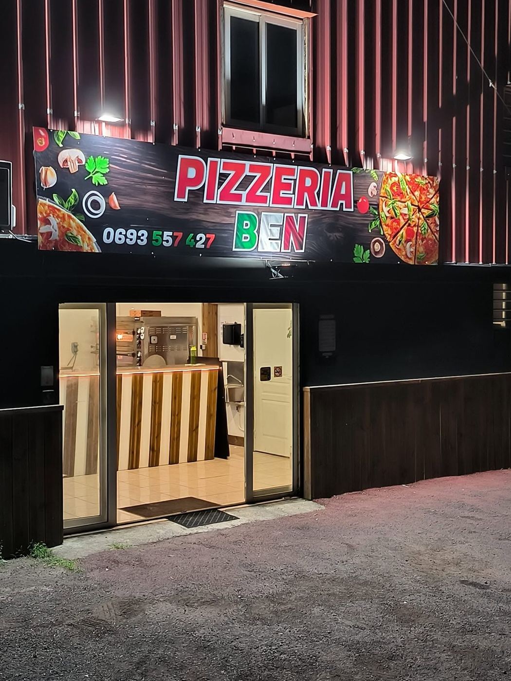 Devanture de la Pizzeria BEN éclairée le soir, chemin Grand Canal